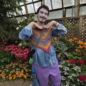 a clown doing a cute pose in front of a flower garden